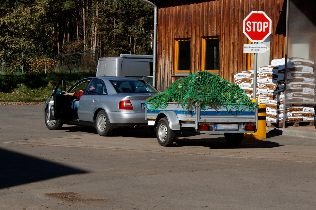 Anlieferung von Grünabfällen am Kompostwerk: Kraftfahrzeug, Anhänger, Waage, Kompostsäcke, Stop-Schild