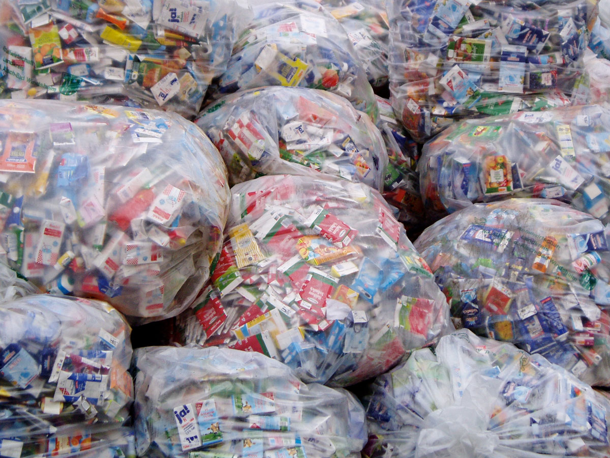 Verpackte Kunststoffabfälle an einer Sammelstelle: Plastiksäcke gefüllt mit Milch- und Getränkekartons (Tetra Pak)