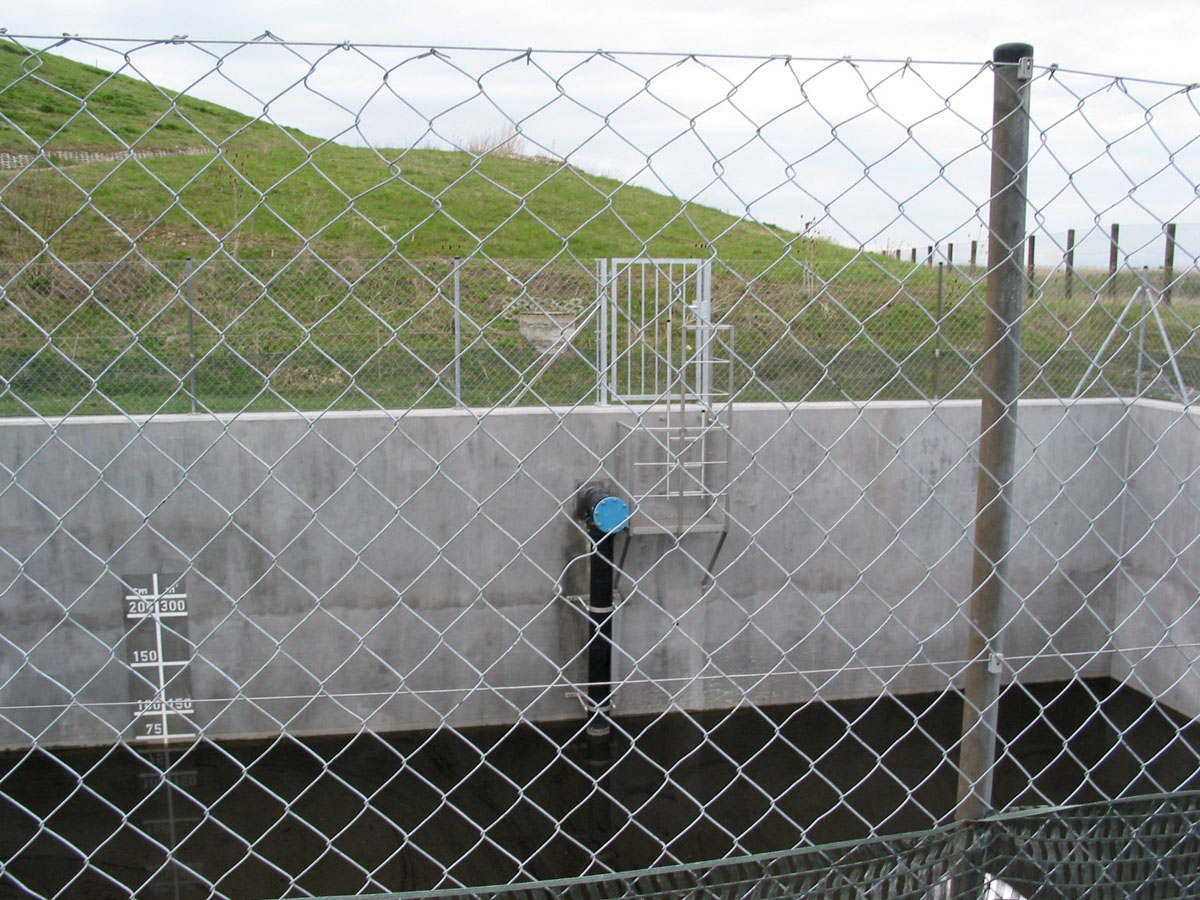 Sickerwasserbecken auf einer Hausmülldeponie: Zaun, Deponieglände