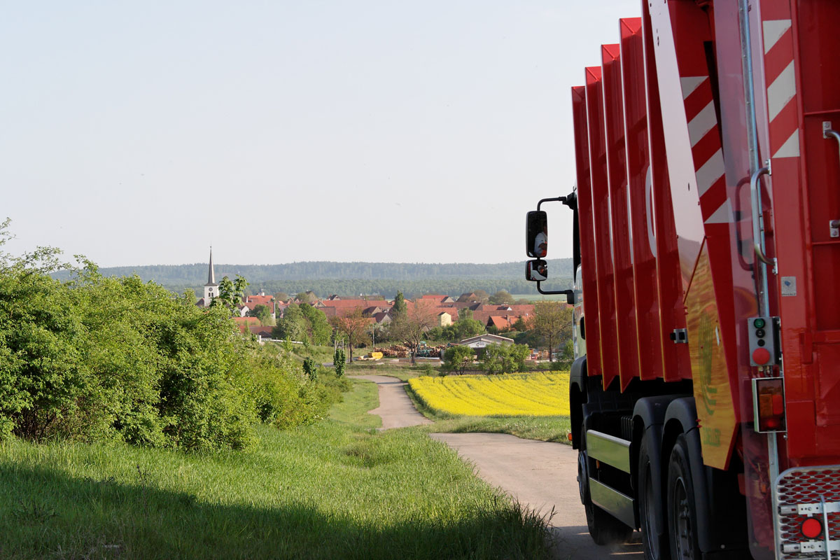 Die Müllabfuhr kommt: Ein Müllfahrzeug nähert sich einem fränkischen Dorf