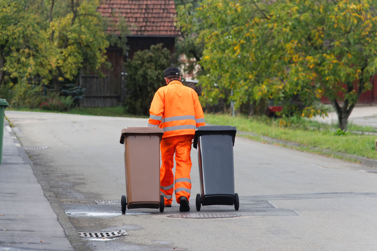 Verteilung neuer Mülltonnen: Müllwerker in Orange, graue Restabfalltonnen, braune Biotonnen, Straße, Haus, Häuser, Gebäude, Ortschaft