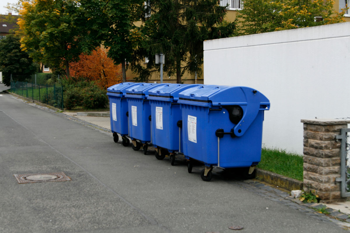 Blaue Papiercontainer stehen am Straßenrand zur Müllabfuhr bereit