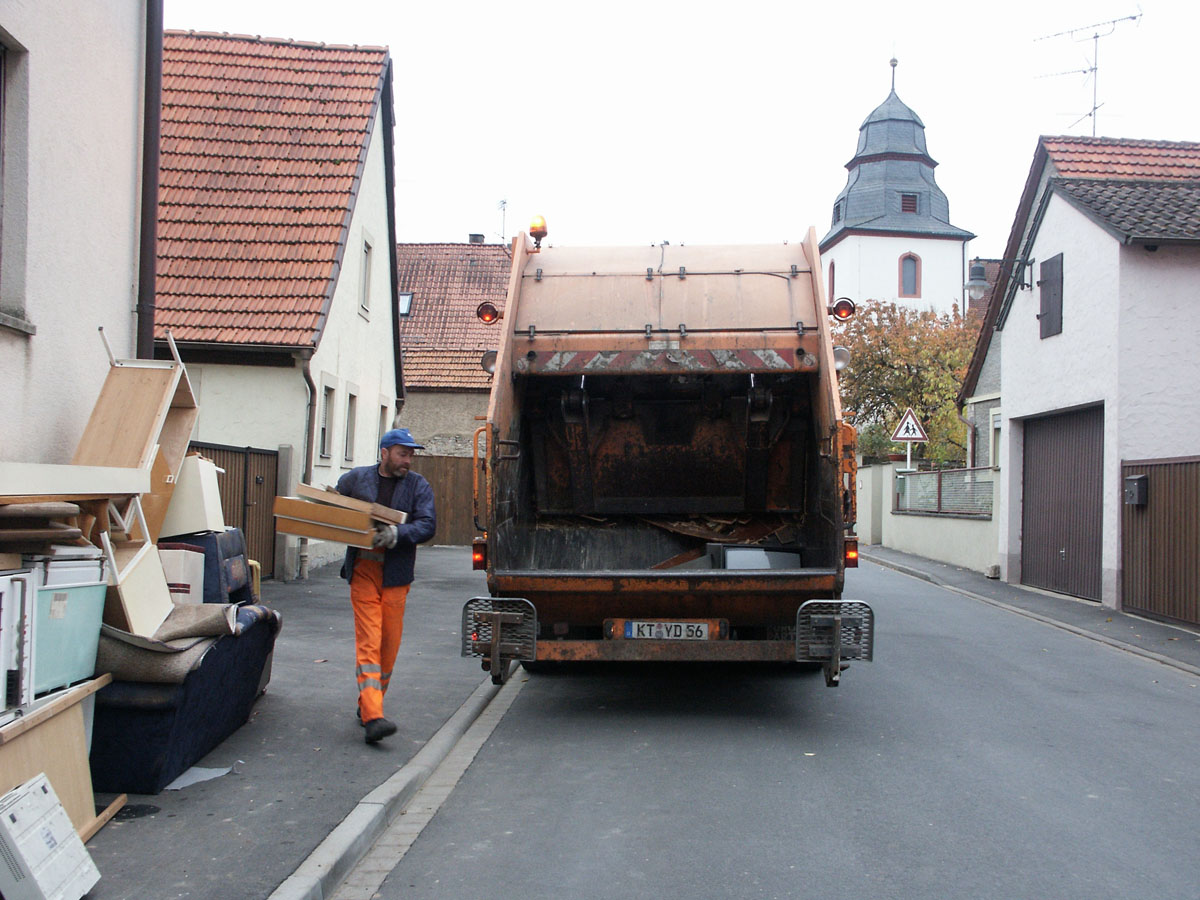Sperrabfallabfuhr: Müllwerker lädt Sperrabfall in das Müllfahrzeug (Hecklader)
