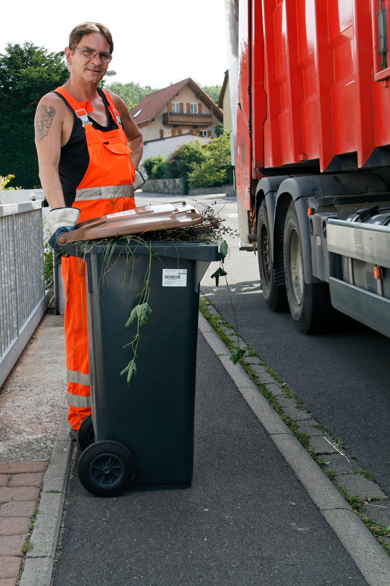 Leerung der Biotonne: Müllwerker mit brauner Tonne am Hecklader-Müllfahrzeug