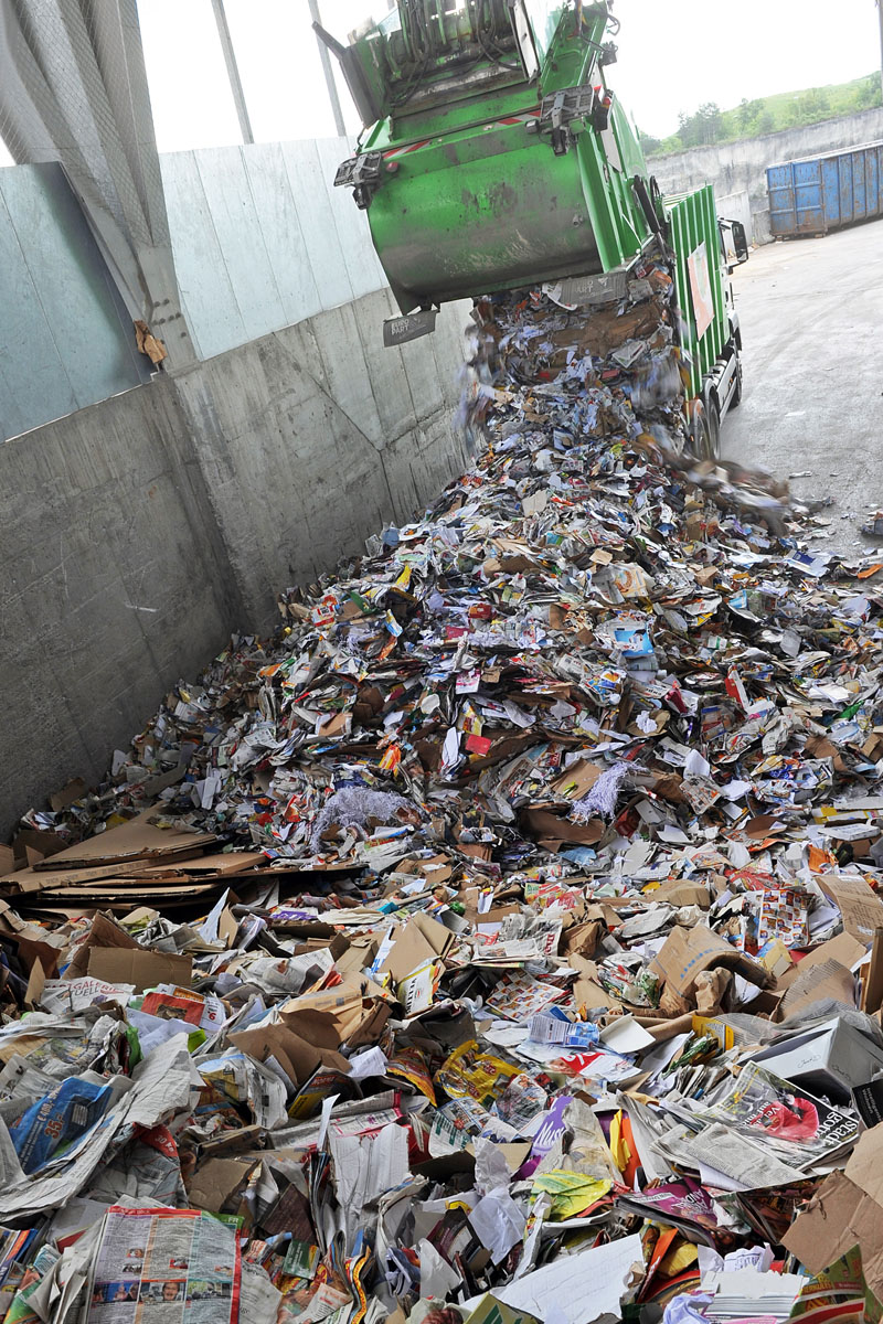 Umschlag von Altpapier: Müllfahrzeug entlädt Papierabfälle in der Halle einer Umladestation