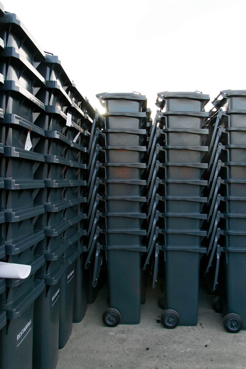 Neue Restabfalltonnen warten auf Auslieferung an die Kunden: Graue Abfallbehälter in Stapeln