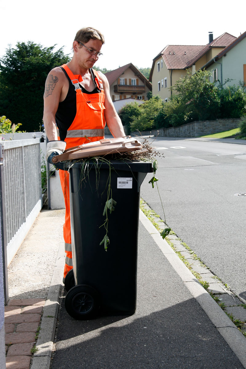 Müllwerker mit Bioabfallbehälter (brauner Deckel, grauer Korpus, MGB 120 Liter), Abfuhr, Leerung