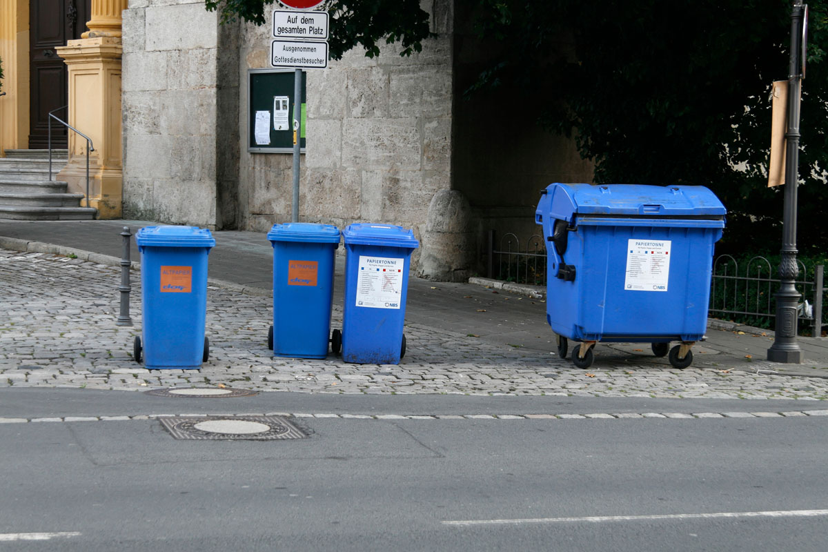 Blaue Papiertonnen (MGB 240 Liter) und Papiercontainer (MGB 1100 Liter) stehen an der Straße zur Abfuhr bereit