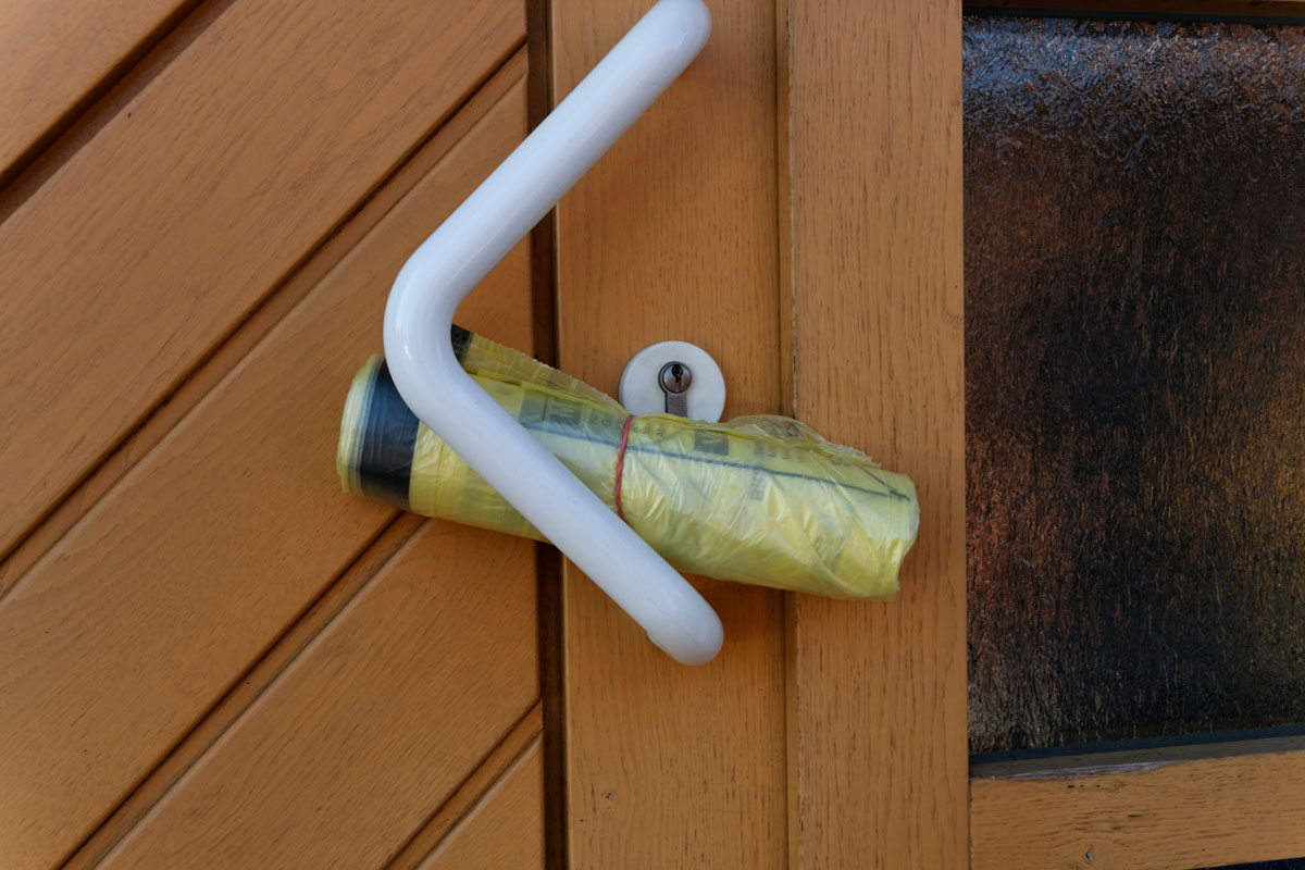 Verteilung des Gelben Sacks: Rolle mit Gelben Säcke steckt im Griff einer Haustür