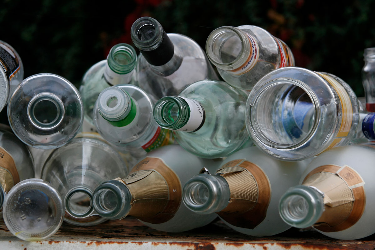 Nahaufnahme von Weißglasflaschen auf einem überfüllten Glascontainer: Weinflaschen, Sektflaschen, Saftflaschen, Konservenglas