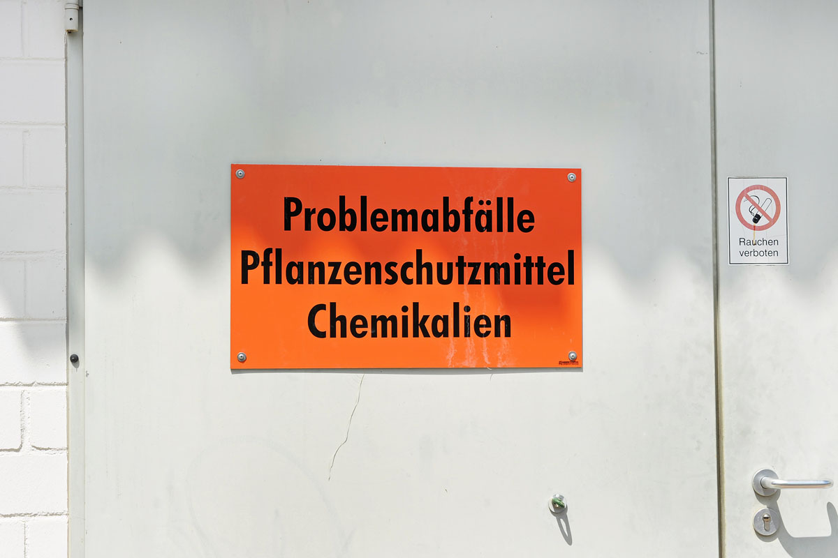 Oranges Hinweisschild an der Tür eines Problemmüll-Zwischenlagers auf einem Wertstoffhof: Problemabfälle, Pflanzenschutzmittel, Chemikalien