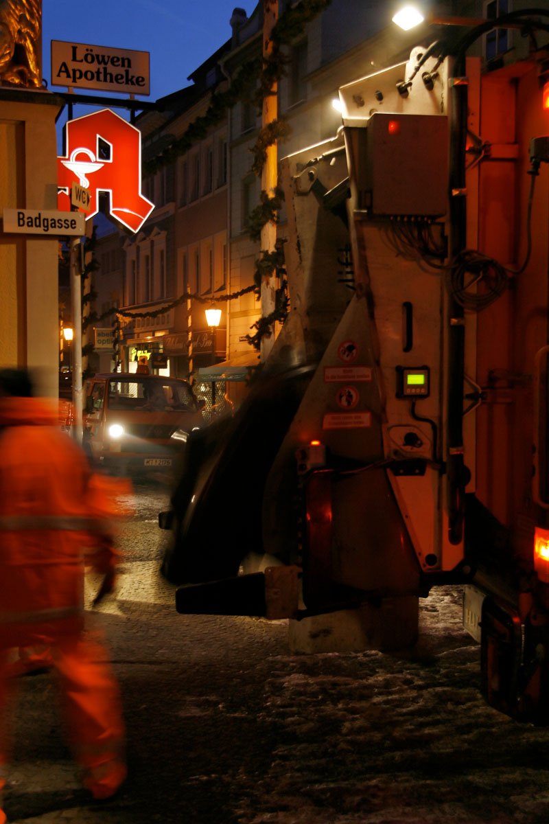 Harter Job: Müllwerker bei der Müllabfuhr im Winter bei Dunkelheit, Stadt, Straße