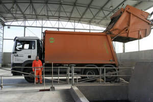 Müllumladestation, oranges Müllfahrzeug, Hecklader, Mülllaster