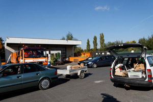 Reger Andrang an einem Wertstoffhof: Anlieferer, Anlieferung, PKW, PKW-Anhänger, Betriebsgebäude