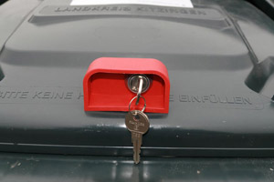 Mülltonne zum Verschließen: Schwerkraftschloss an einer Restabfalltonne mit Schlüssel