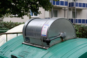 Müllschleuse: Grüner Müllcontainer aus Metall (MGB 1.100 Liter) an einem Mehrfamilienhaus (Wohnblock)