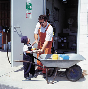 Kleiner Junge liefert Problemmüll in einem Schubkarren am Wertstoffhof an: Lackdose und Kanister mit Schadstoffen