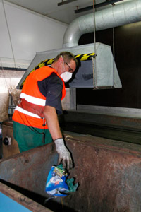 Auslese von Störstoffen im Kompostwerk: Müllwerker, Sortierkabine, Abwurfschacht, Plastikteile, Absauganlage, Förderband, Mundschutz