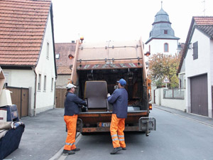 Die Sperrmüllabfuhr ist da: Müllwerker laden Sessel in das Müllfahrzeug