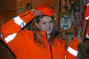 Charmante Müllwerkerin am Heck eines Müllfahrzeugs