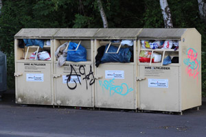Überfüllte Altkleidercontainer, öffentlicher Containerstandort, Plastiktüten, Graffiti