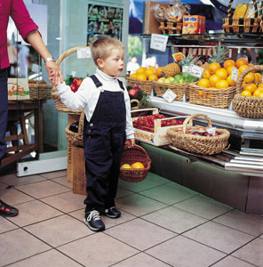 Abfallarmes Einkaufen von Kindesbeinen an: Junge kauft unverpacktes Obst in einem Supermarkt