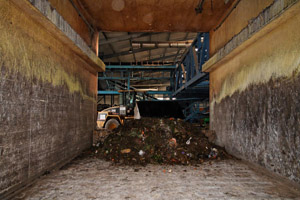 Tunnelkompostierung in einem Kompostwerk: Radlader befüllt Tunnel mit Bioabfällen