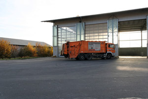 Müllumladestation, oranges Müllfahrzeug, Hecklader, Mülllaster, Müllauto