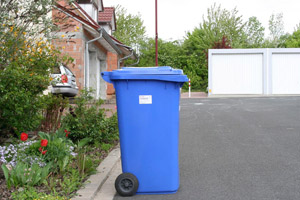Blaue Papiertonne (MGB 240 Liter) wartet am Straßenrand auf die Müllabfuhr