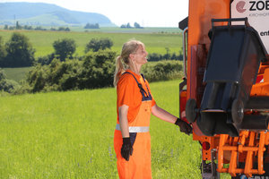 Müllwerkerin, Leerung Biotonne in das Müllfahrzeug, Heckladermüllfahrzeug, Müllauto, Schüttung, orange Arbeitsschutzkleidung