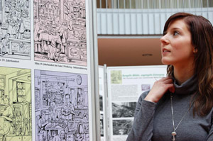 Findet die Geschichte des Mülls ungemein spannend: Attraktive Frau betrachtet Bildtafel der Abfallausstellung