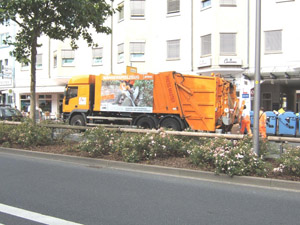 Müllabfuhr in der Stadt: Leerung der blauen Papiercontainer mit einem Hecklader-Müllfahrzeug