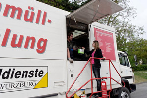 Mobile Problemabfallsammlung: Junge Frau gibt Problemabfälle (Farbeimer, Feuerlöscher, Farbdose) am Problemmüllmobil ab