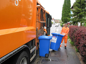 Neue Technik: Müllwerker leert blaue Papiertonnen mit dem Seitenlader-Müllfahrzeug