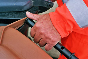 Mülltonnenleerung: Müllwerker hat eine braune Biotonne fest im Griff