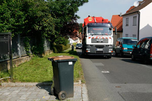 Müllabfuhr: Biotonne mit braunem Deckel und grauem Rumpf (Korpus), Müllfahrzeug, Seitenlader