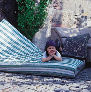 So schön kann Sperrmüll sein: Kind macht es sich auf einer Matratze bequem, dahinter ein Sofa