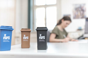 Mülltonnen anmelden, Anmeldung, junge Frau, Formular, ausfüllen, Mülltönnchen, kleine Mülltonnen, Schreibtisch, Büro